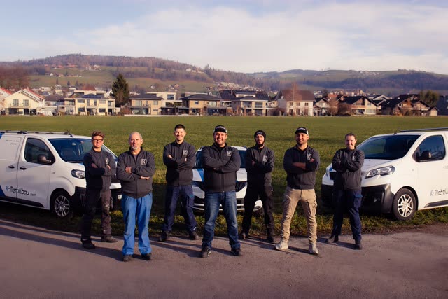 Das Team der K-Metallbau GmbH zwischen den beiden Firmenfahrzeugen