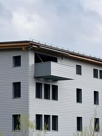 Vorgehängter anthrazitfarbener Metallbalkon an der Fassade eines mehrgeschossigen Gebäudes