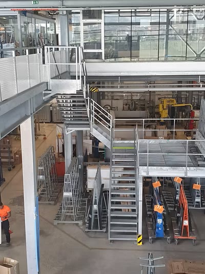 Verzinkte Stahlpodeste, Zugangstreppen und Geländer auf mehreren Ebenen in einer Produktionshalle