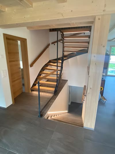 Offene Innentreppe mit blaugrauer Stahlwange, Holzstufen und Geländer mit horizontalen Seilen in einem Holzelementbau