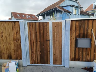 Doppelflügeliges Tor mit verzinktem Metallrahmen und Holzfüllung in einem Sichtschutzzaun