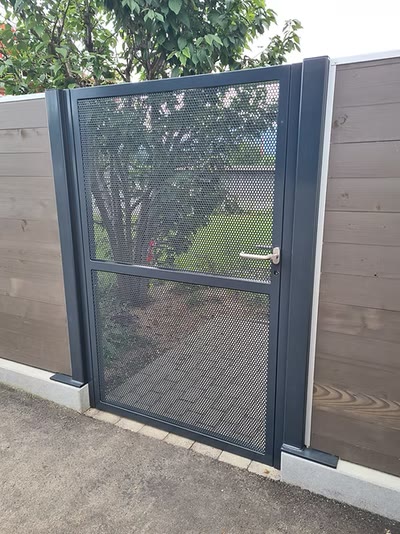 Anthrazitfarbenes Gartentor mit Streckmetallfüllung zwischen Holzzaun und Sichtschutzwand