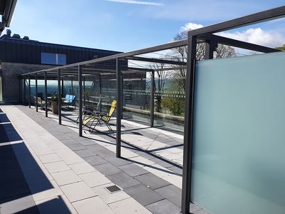 Seitenansicht einer Terrassenüberdachung mit anthrazitfarbenem Metallrahmen und Glasfeldern