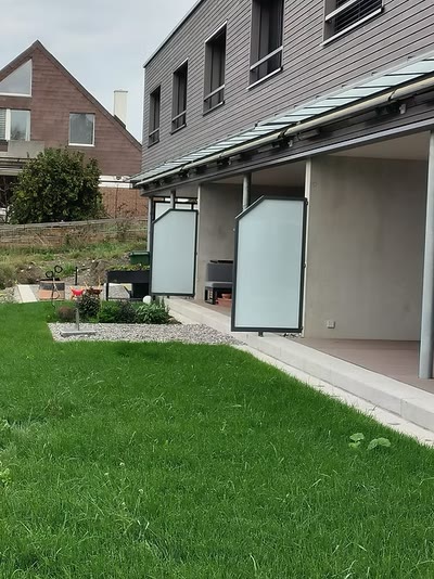 Vordach mit Glasfeldern und zwei satinierten Sichtschutzelementen an einem modernen Wohnhaus